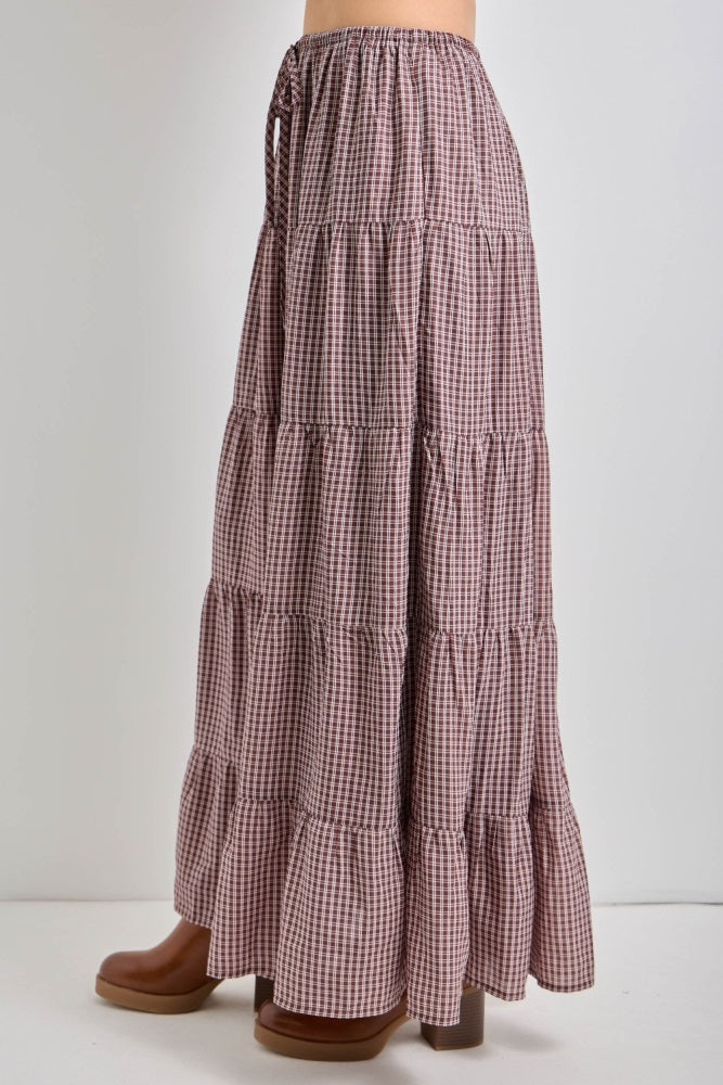 long tiered maxi skirt in a brown and white gingham pattern with an elastic waistband and side ties