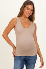woman wearing a beige maternity tank top and showing her baby bump while smiling
