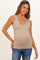 woman wearing a beige maternity tank top and showing her baby bump while smiling