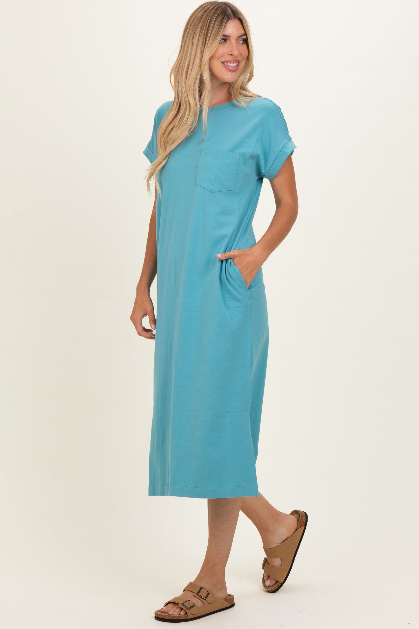 woman wearing a teal short sleeve maxi dress with a pocket and side pockets, styled with brown sandals