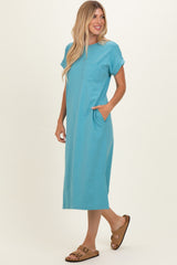 woman wearing a teal short sleeve maxi dress with a pocket and side pockets, styled with brown sandals