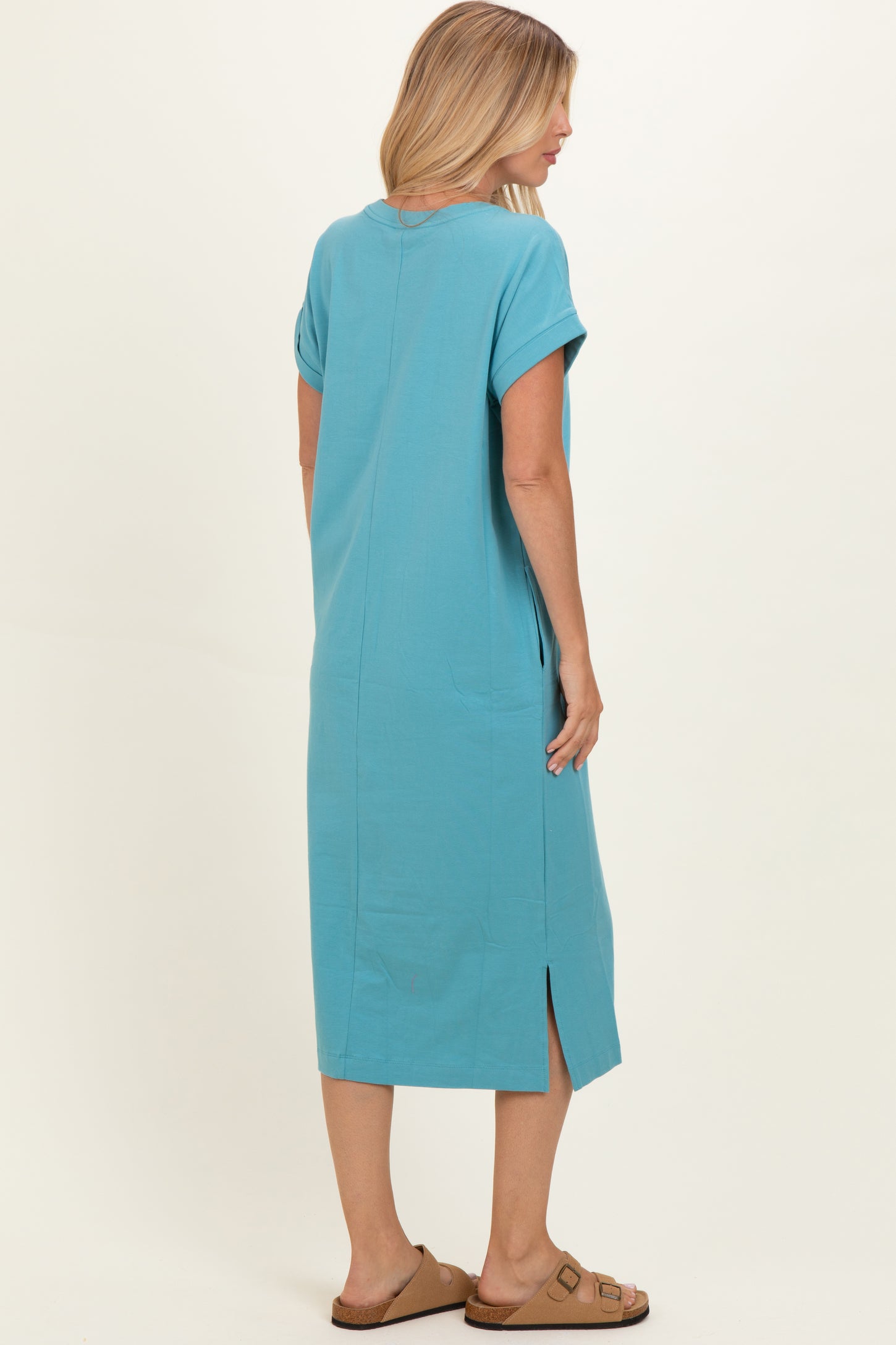 woman wearing a turquoise short sleeve maxi dress with side slits and a relaxed fit, view from the back