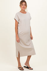 woman wearing a light beige maternity dress with short sleeves and a side slit, showing her baby bump