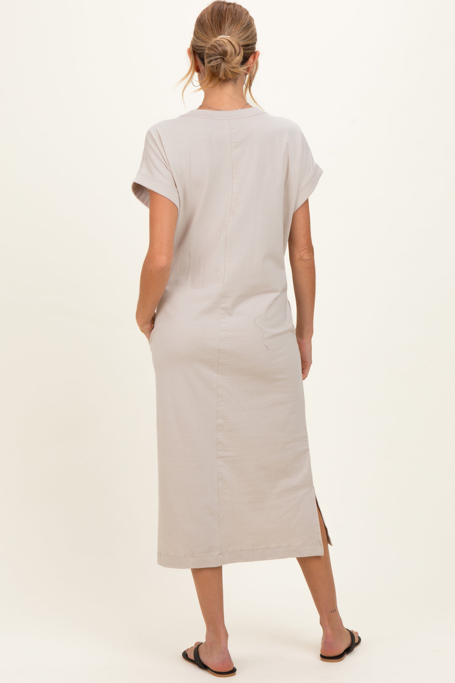 woman wearing a light gray maternity dress with short sleeves and a side slit, viewed from the back