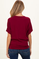 woman wearing a burgundy maternity top with short sleeves, showing the back view with a relaxed fit