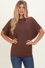 woman wearing a brown short sleeve oversized top paired with blue jeans