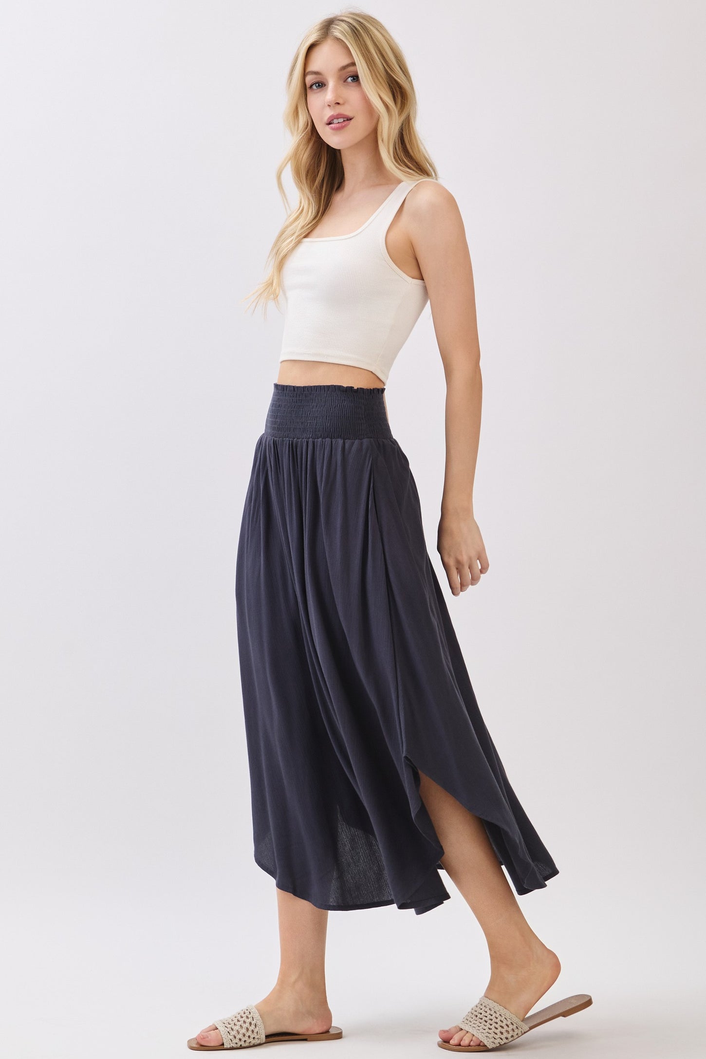 woman wearing a white cropped tank top and a dark navy flowy midi skirt