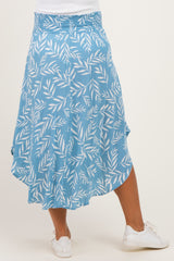 woman wearing a light blue maternity skirt with a leaf pattern and asymmetrical hem, shown from the back