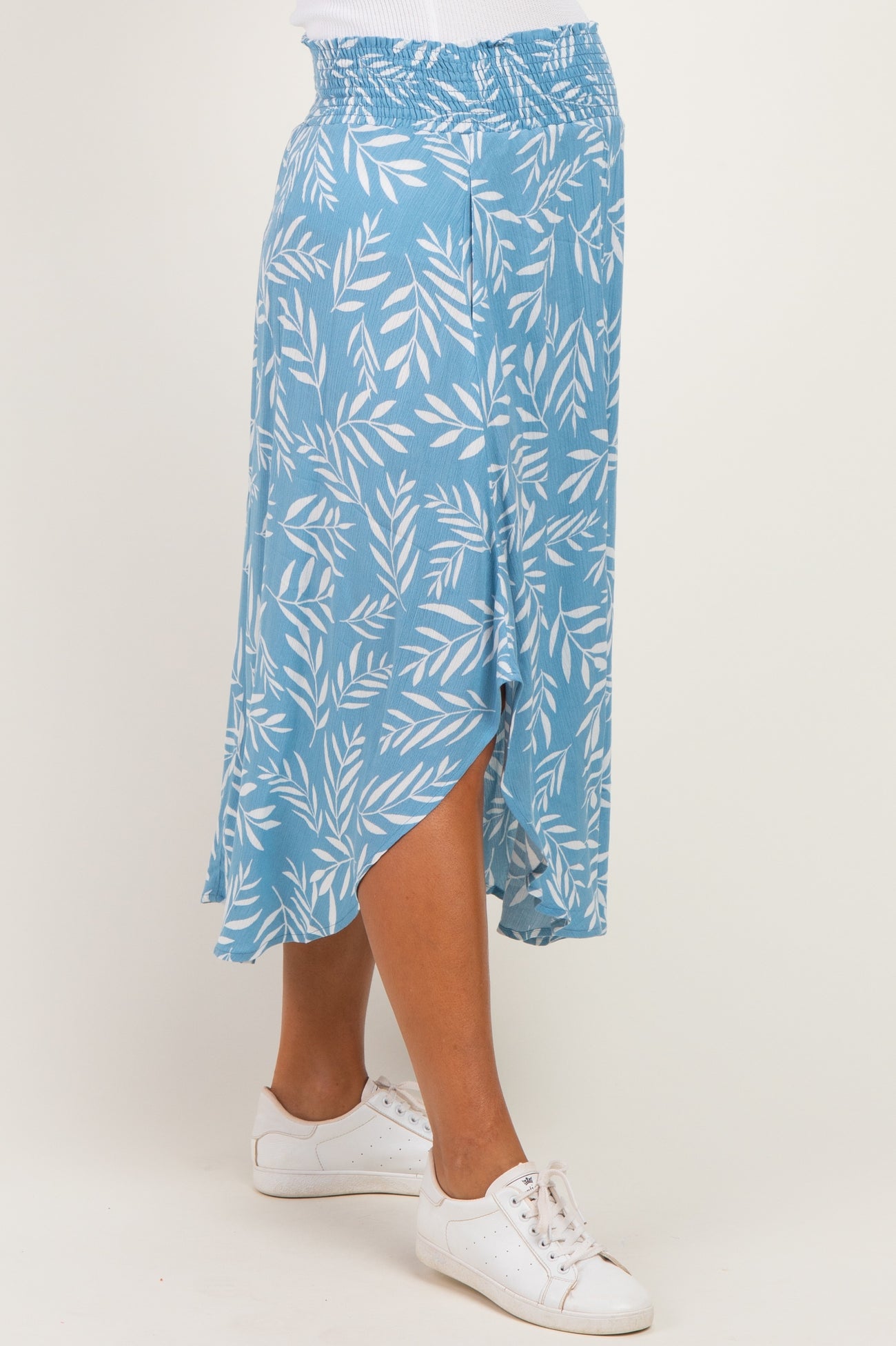 woman wearing a light blue maternity skirt with a leaf print and an asymmetrical hem