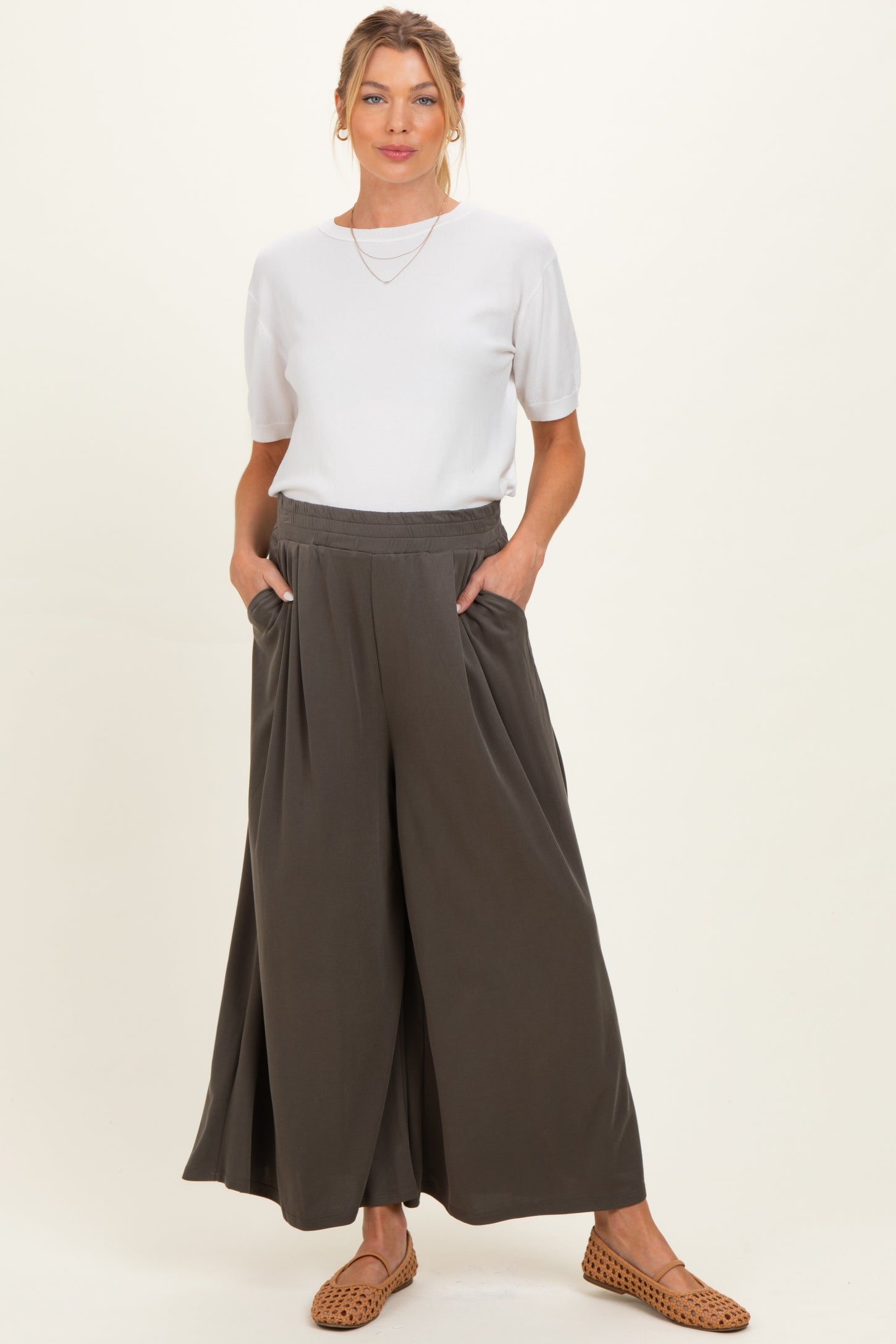 woman wearing a white short sleeve top and dark green maternity wide-leg trousers with pockets