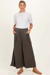 woman wearing a white short sleeve top and dark green maternity wide-leg trousers with pockets