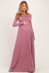 woman wearing a mauve off-the-shoulder maxi maternity dress and holding her baby bump