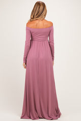 woman wearing a mauve off-the-shoulder maternity maxi dress with long sleeves and flowy skirt, showing a baby bump from the back