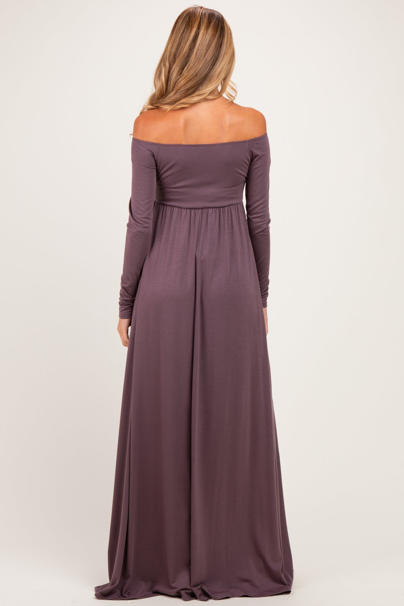 woman wearing a long mauve off-shoulder maternity gown, showing a flowing silhouette from the back