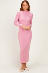 woman wearing a pink long sleeve ribbed maxi dress with a high neck and fitted silhouette