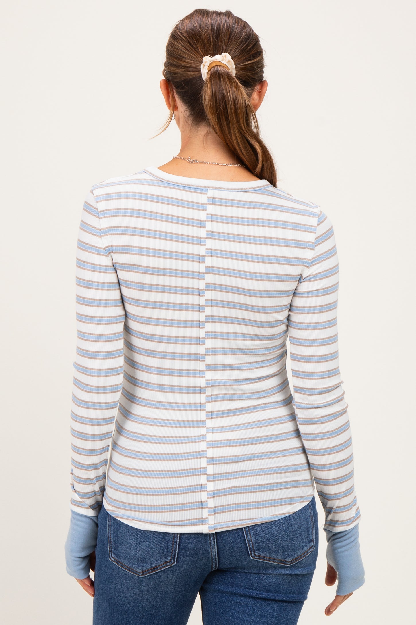 woman wearing a striped long sleeve maternity top with a button detail at the back, styled with blue denim jeans