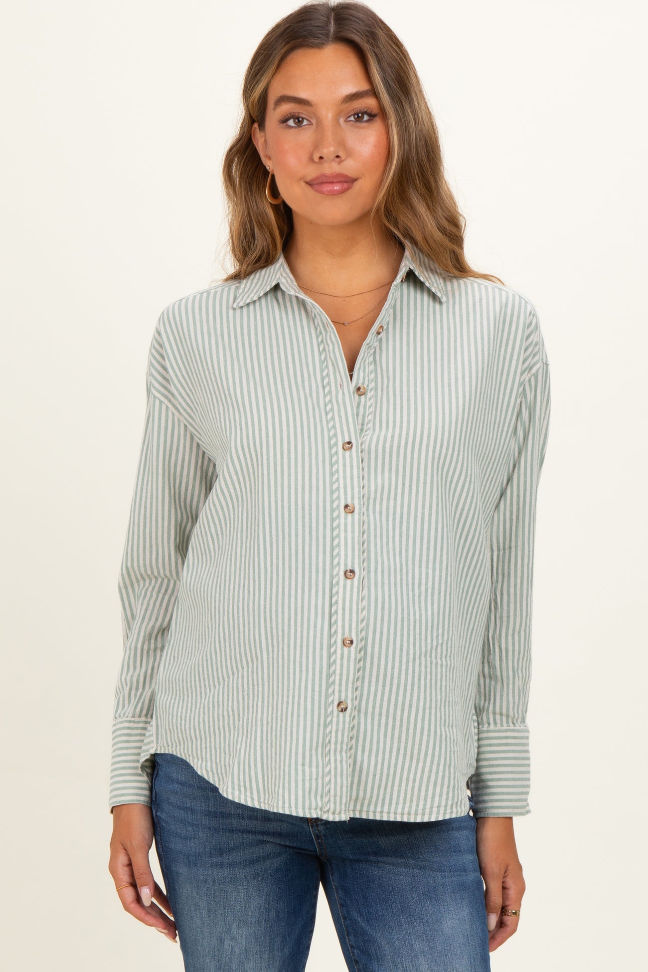 woman wearing a light green and white striped maternity shirt with button details and long sleeves