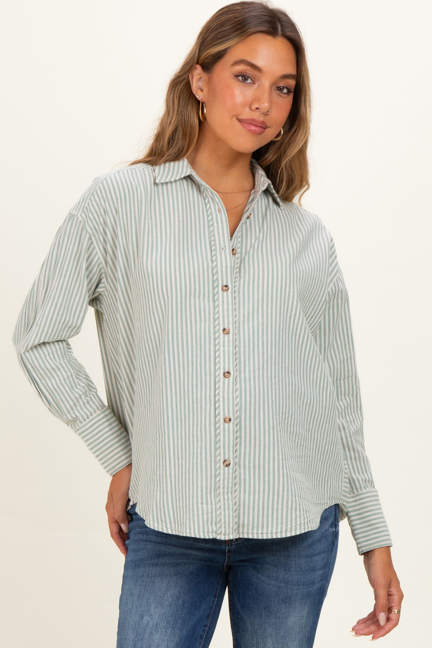 woman wearing a green and white striped maternity button-up shirt with long sleeves and a relaxed fit
