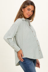 woman wearing a light green and white striped maternity shirt, showing her baby bump, paired with blue jeans