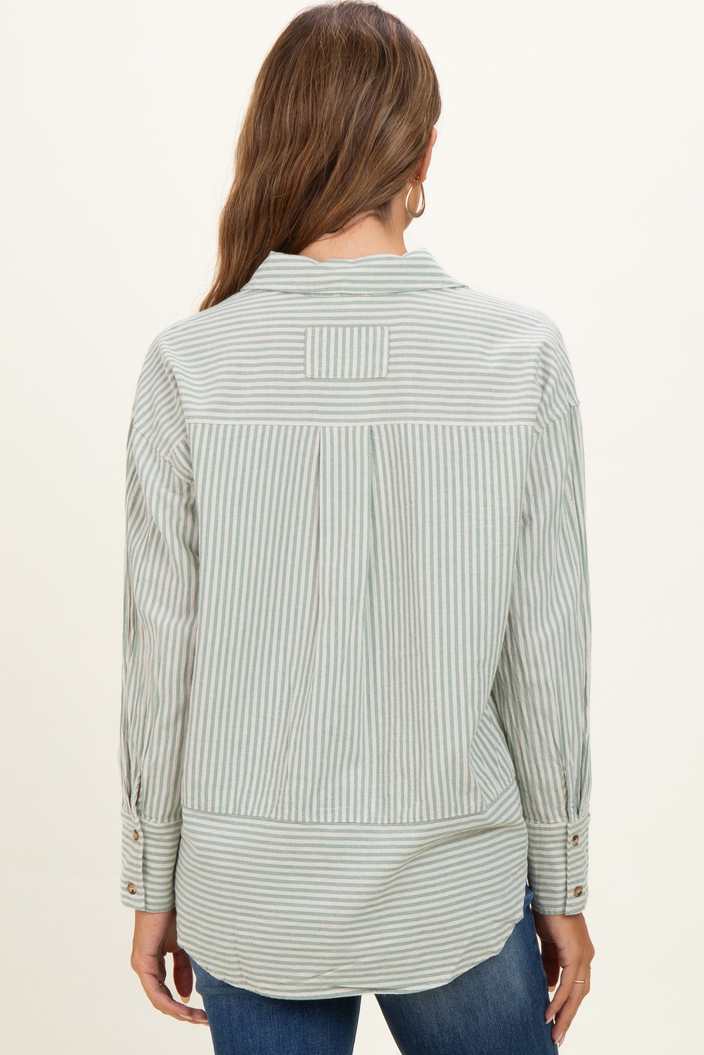 woman wearing a green and white striped maternity button-up shirt, shown from the back