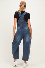 woman wearing a dark blue maternity denim overalls with a relaxed fit and pockets, styled with a black t-shirt underneath