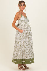 woman wearing a floral print maternity maxi dress with a tie waist and pockets, showcasing her baby bump