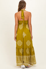 woman wearing a mustard yellow maternity maxi dress with a halter tie and printed patterns