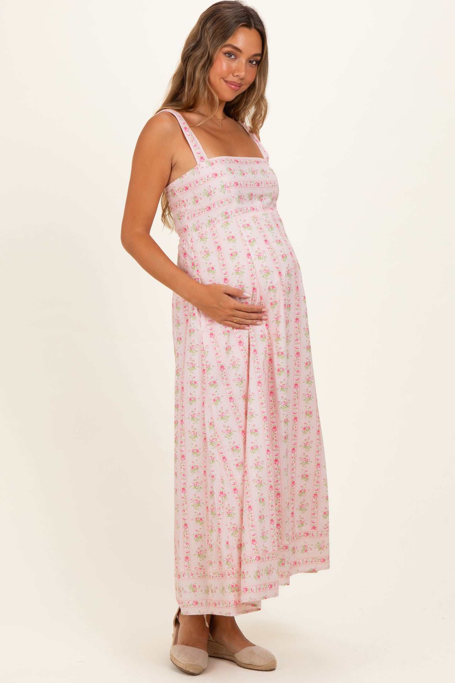 woman wearing a pink floral maternity maxi dress with adjustable straps and a baby bump