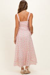 woman wearing a pink floral maternity maxi dress with smocked bodice and adjustable straps