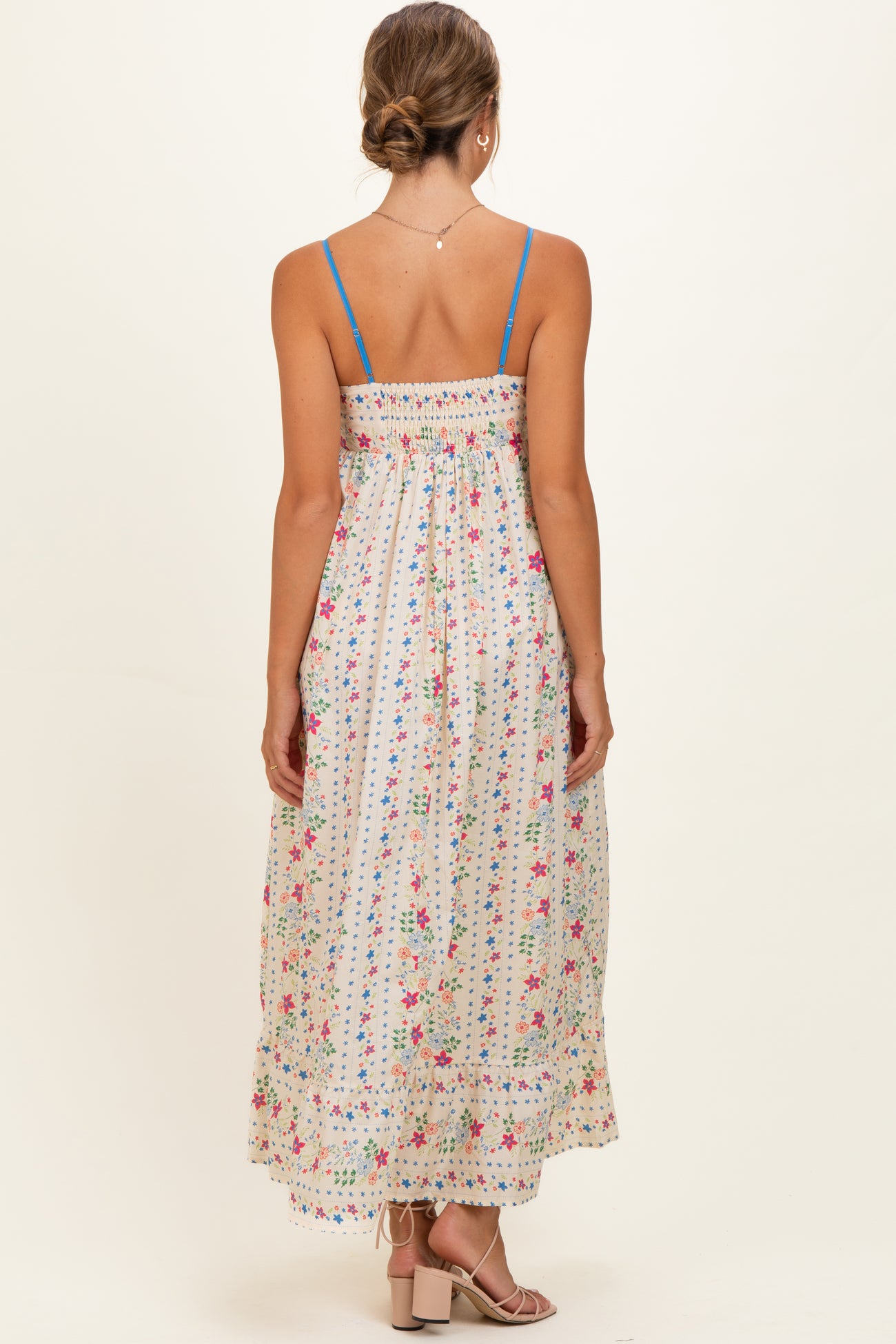 woman wearing a floral print maternity maxi dress with a smocked back and thin blue straps, showing her baby bump