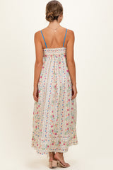 woman wearing a floral print maternity maxi dress with a smocked back and thin blue straps, showing her baby bump