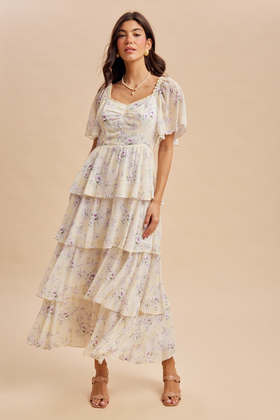 woman wearing a pastel yellow tiered maxi dress with floral print and puff sleeves