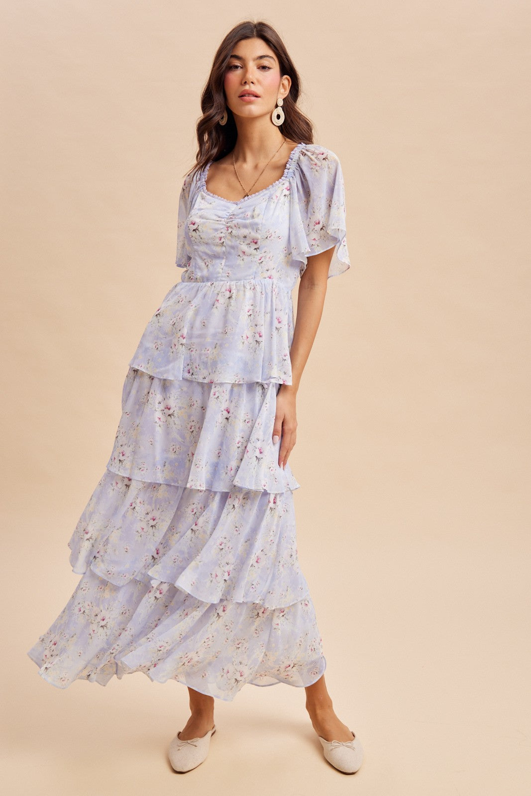 woman wearing a light blue floral tiered maxi dress with short sleeves and a scoop neckline