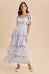 woman wearing a light blue floral tiered maxi dress with short sleeves and a scoop neckline