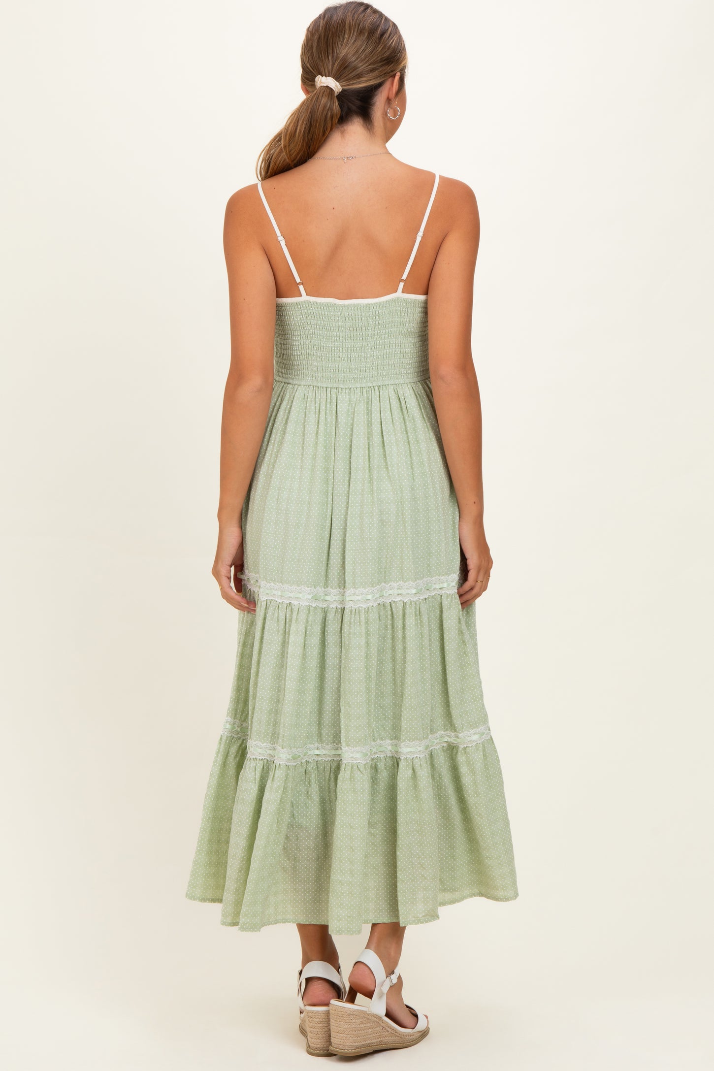 woman wearing a green tiered maternity dress with a smocked bodice and spaghetti straps, shown from the back