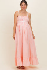 woman wearing a light pink maternity maxi dress with spaghetti straps and ruffle hem