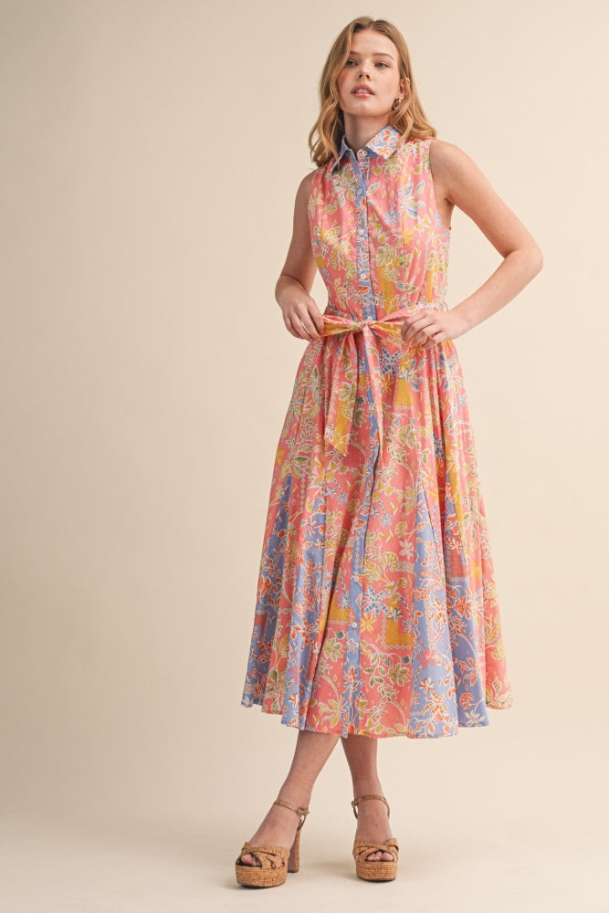 woman wearing a sleeveless floral maxi dress with a collared neckline and belted waist in pastel colors