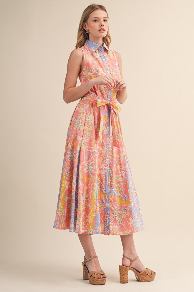 woman wearing a pink and blue floral midi dress with a collared neck and tie waist detail