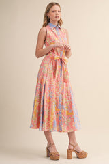 woman wearing a pink and blue floral midi dress with a collared neck and tie waist detail