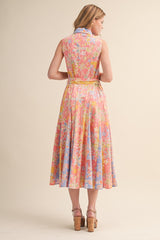 woman wearing a sleeveless pastel floral dress with a flared skirt and a tie at the waist, viewed from the back