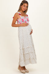woman wearing a floral print maternity maxi dress with a smocked bodice and ruffled tiers, holding her baby bump