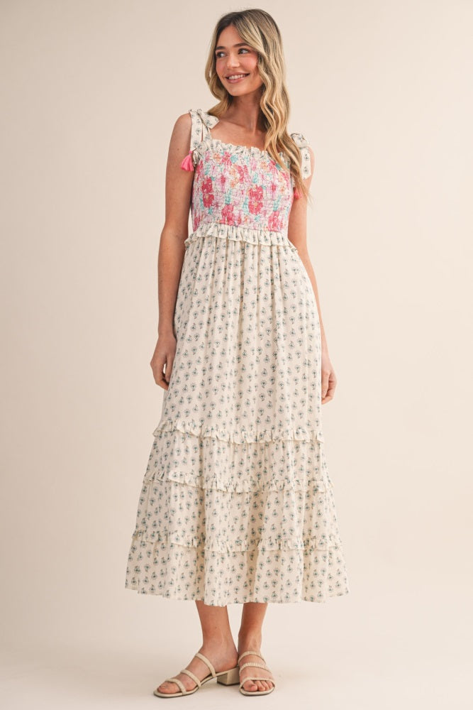 woman wearing a floral print maxi dress with a smocked bodice and ruffled hem, posing against a neutral background