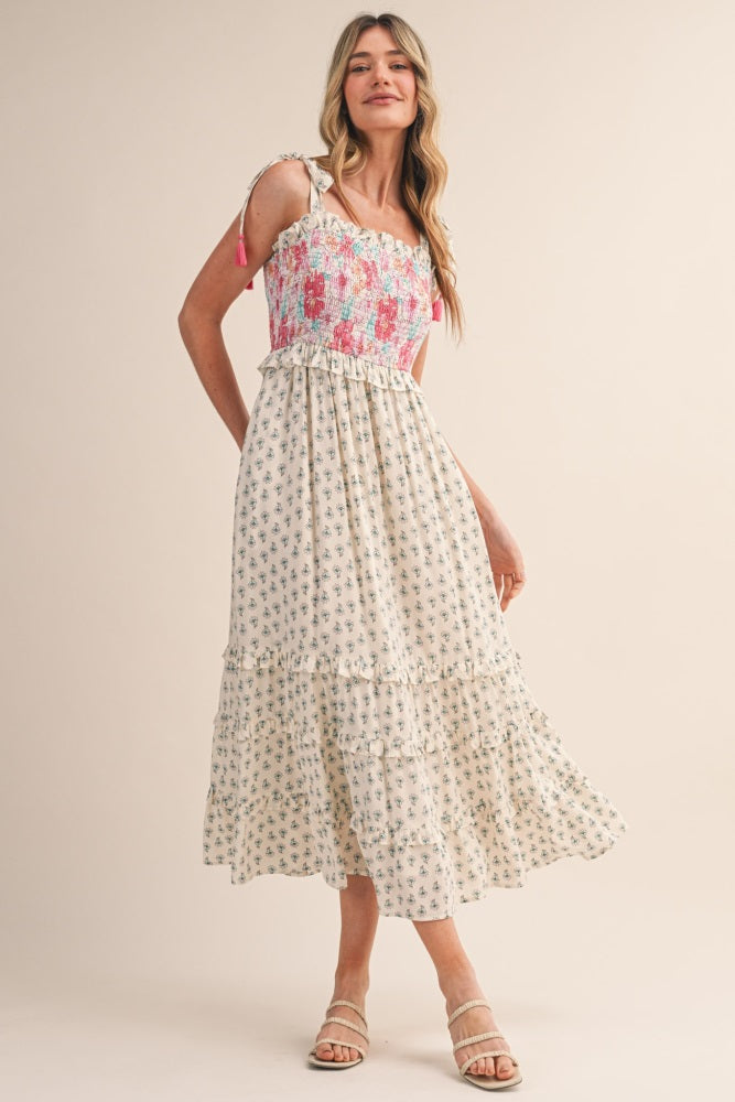 woman wearing a floral print midi dress with a smocked bodice and ruffled hem, posing against a neutral background