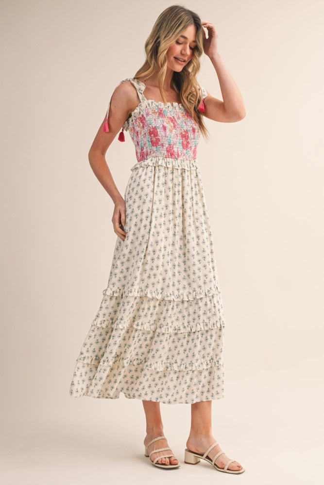 woman wearing a floral maxi dress with smocked bodice and ruffled tiers, styled with shoulder ties and sandals