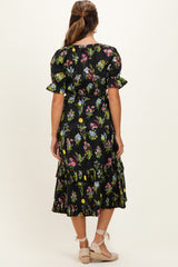 woman wearing a black floral print maternity dress with puff sleeves and ruffle detailing on the skirt