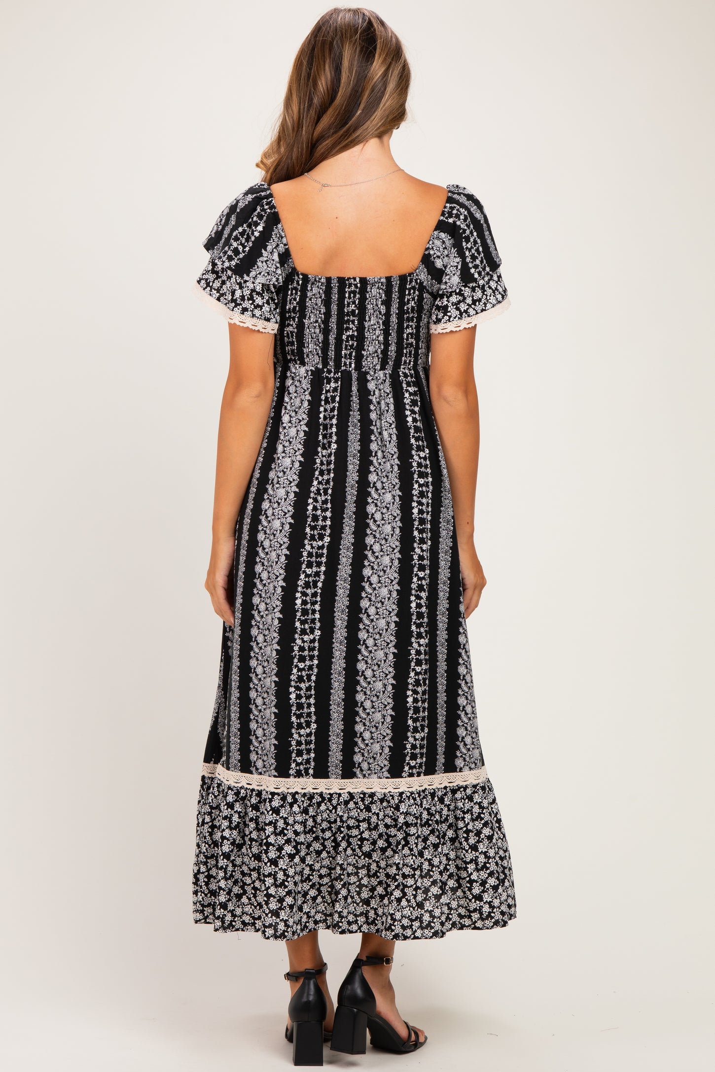 woman wearing a black and white floral print maternity maxi dress with short sleeves and a ruffled hem