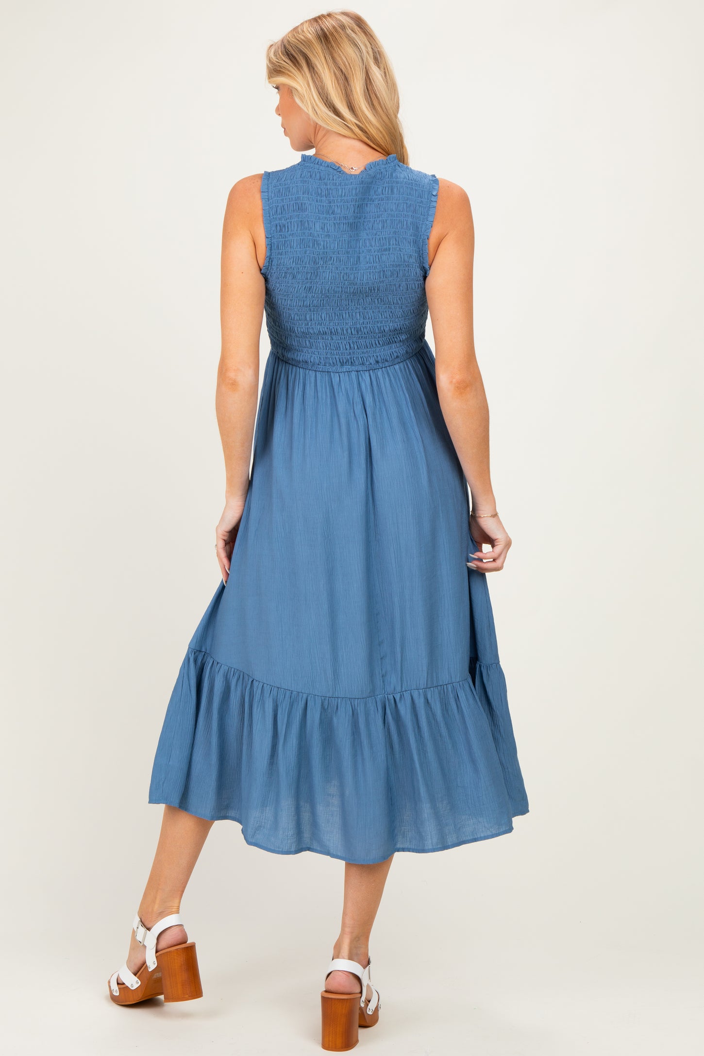woman wearing a blue maternity maxi dress with a smocked bodice and ruffled hem, showing off her baby bump from the back