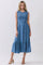 woman wearing a blue sleeveless midi dress with smocked bodice and tiered skirt, standing in a neutral background