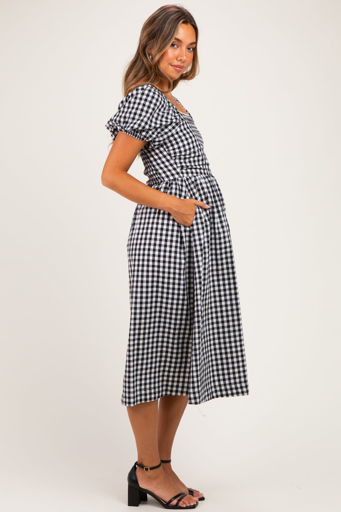 woman wearing a black and white checked maternity dress with puff sleeves and pockets