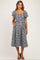 woman wearing a black and white gingham maternity dress with short puff sleeves and pockets, showing a baby bump